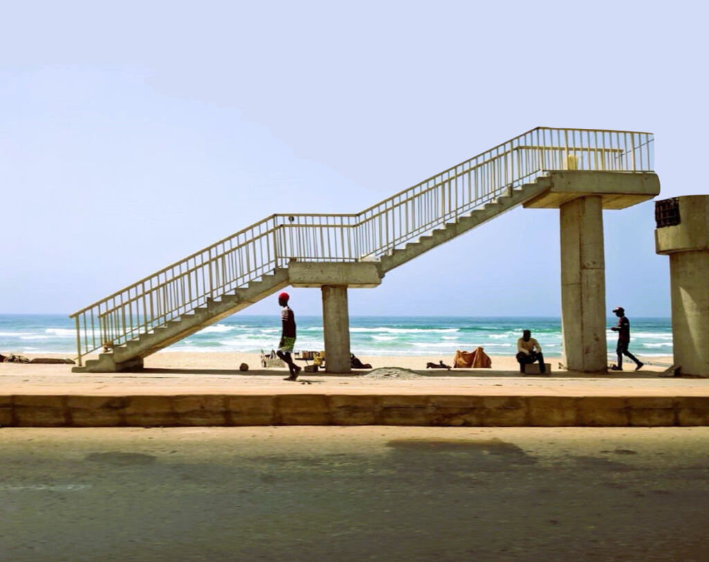 Senegal, Dakar. Foto di persone che camminano davanti al mare.