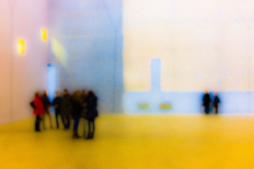 figure di persone sfocate, un gruppo a sinistra e alcune persone distanti a destra, pavimento giallo, all'università di Milano-Bococca